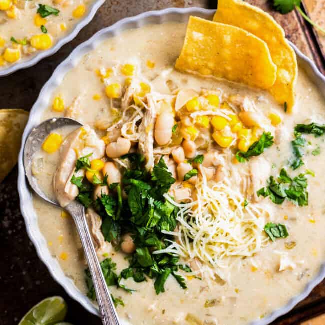 overhead view of a bowl of crockpot white chicken enchilada soup with a spoon.