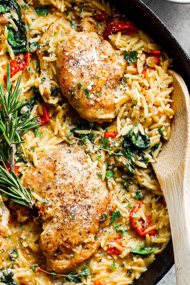 tuscan chicken or orzo in black skillet with wooden spoon
