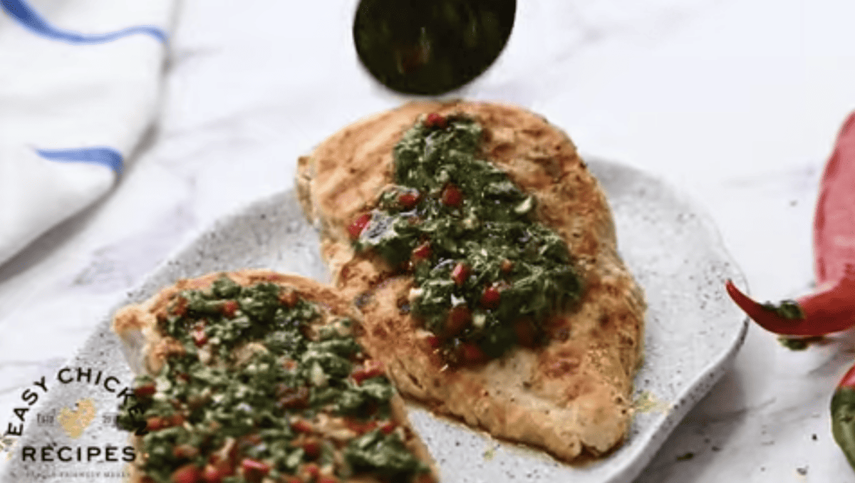 Chimichurri is being spooned on top of cooked chicken breasts.