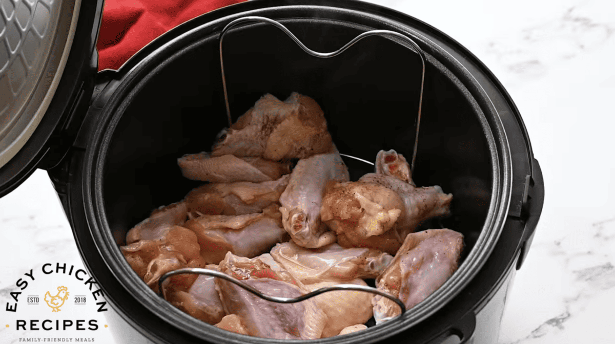 Uncooked wings are placed on a trivet in the instant pot. 