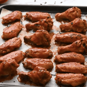 Broiled chicken wings are on a baking sheet.