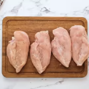 Raw chicken breasts are seasoned.
