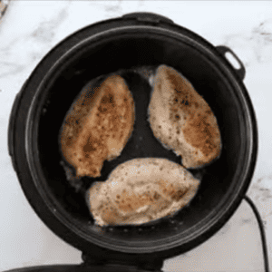 Chicken breasts are being seared in an instant pot.