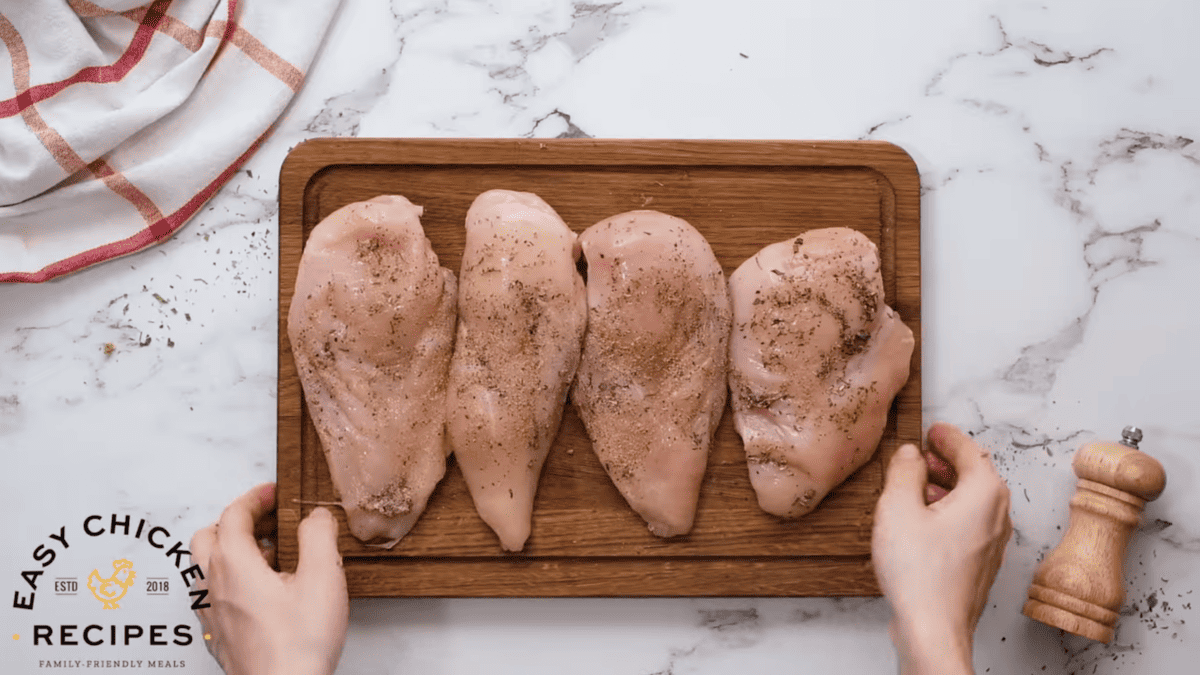 Seasoned chicken breasts are placed on a cutting board. 