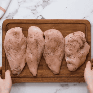 Four chicken breasts ready for Instant Pot shredding, placed on a wooden cutting board.