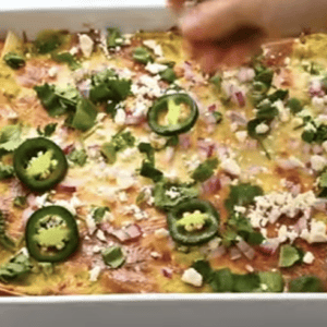 A baked chicken casserole is topped with garnishes.