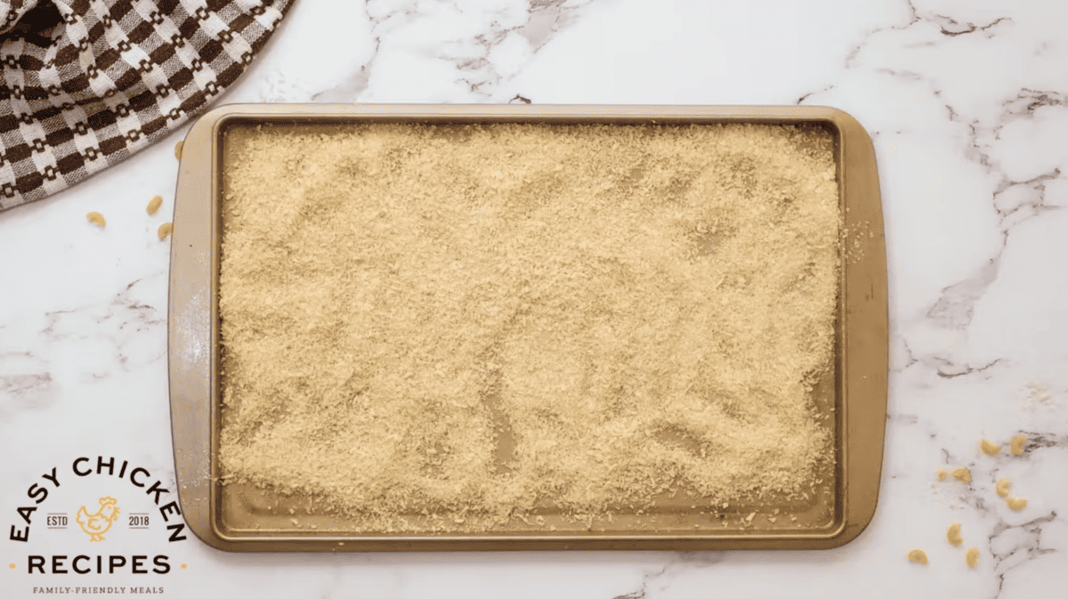 Panko breadcrumbs are spread on a baking sheet.