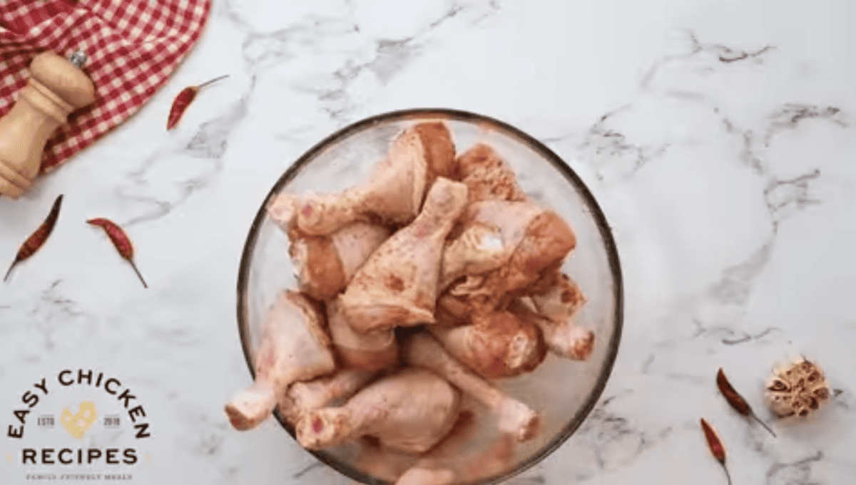 A glass bowl is filled with chicken drumsticks.