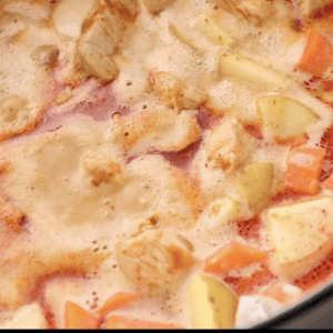 Veggies, broth and coconut milk are mixed together in a pot.