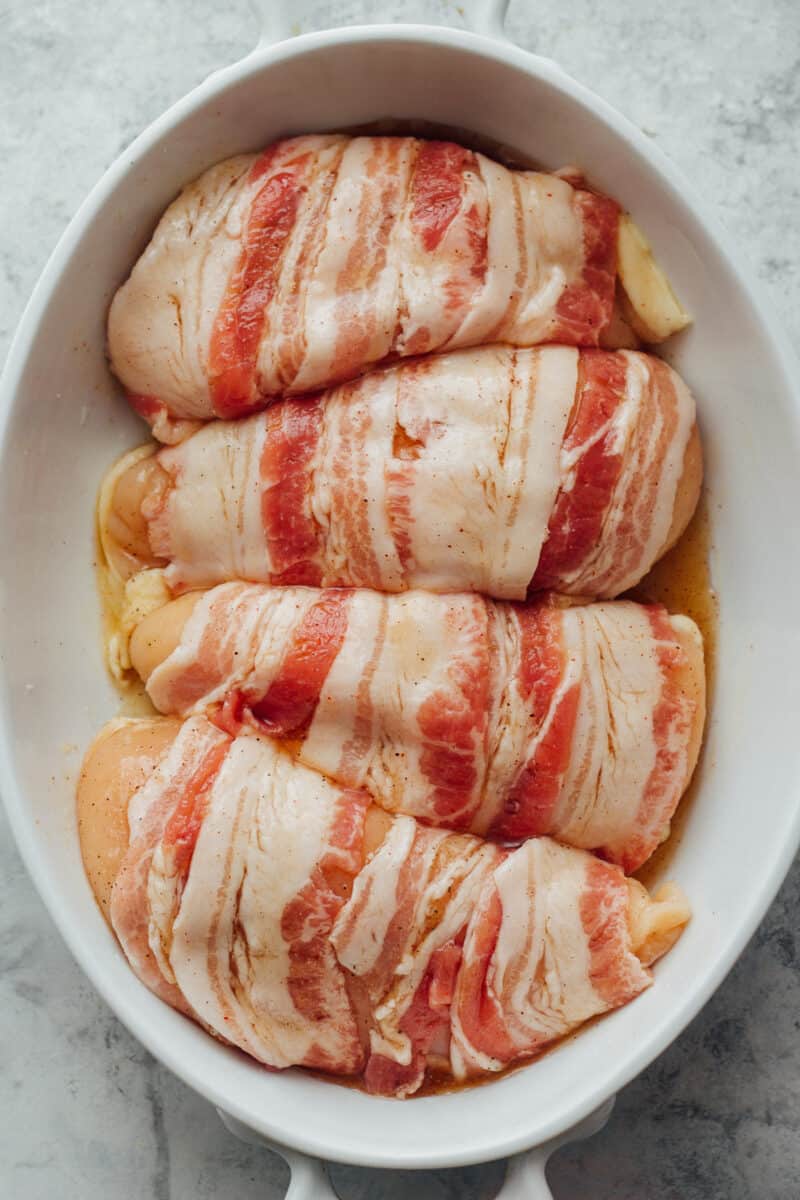 uncooked bacon wrapped chicken breasts in casserole dish