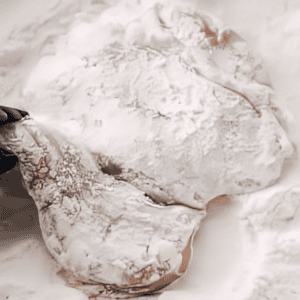 dredging a chicken thigh in flour.