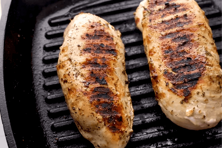 Two grilled chicken breasts on a grill pan.