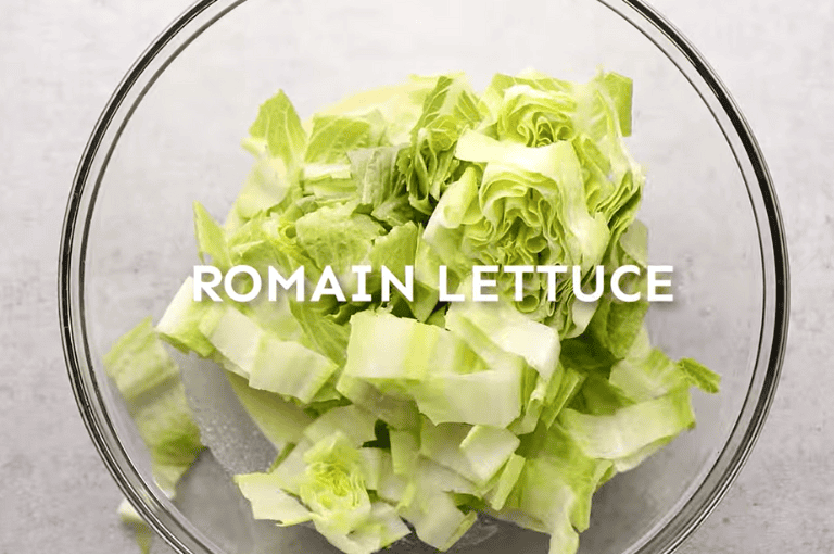 Chopped romaine lettuce and caesar dressing in a glass bowl.
