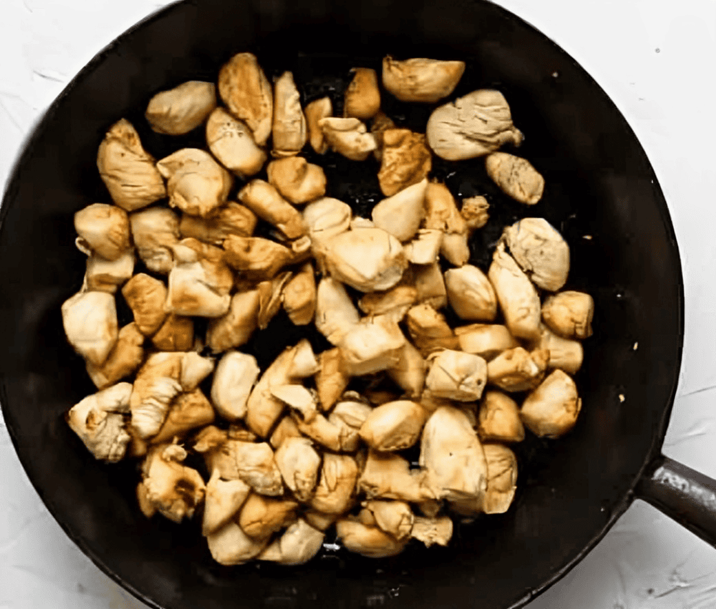 Diced chicken cooking in a skillet.