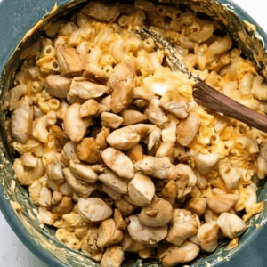 Stirring cooked chicken into a pot of mac and cheese.