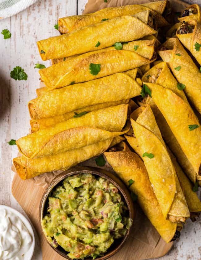 air fried chicken taquitos on platter with avocado salsa