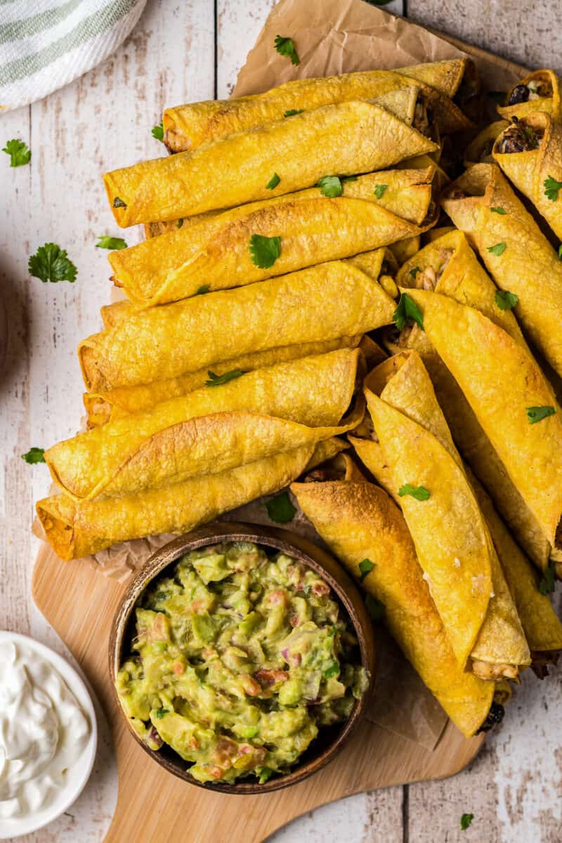 air fried chicken taquitos on platter with avocado salsa