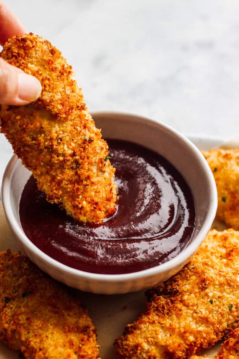 dipping air fried chicken tender in bbq sauce