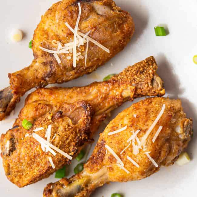 up close air fryer garlic parmesan chicken drumsticks on white plate