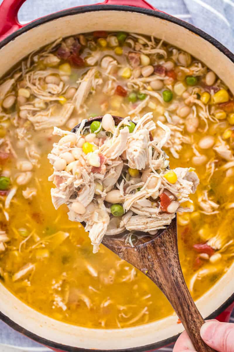 lifting up bacon chicken chili with wooden spoon