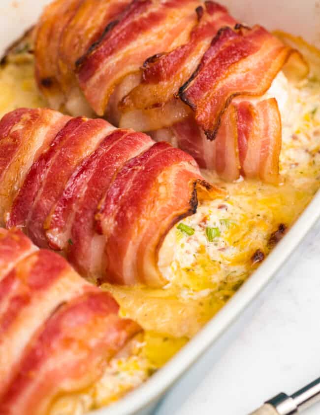 bacon wrapped stuffed chicken in baking dish