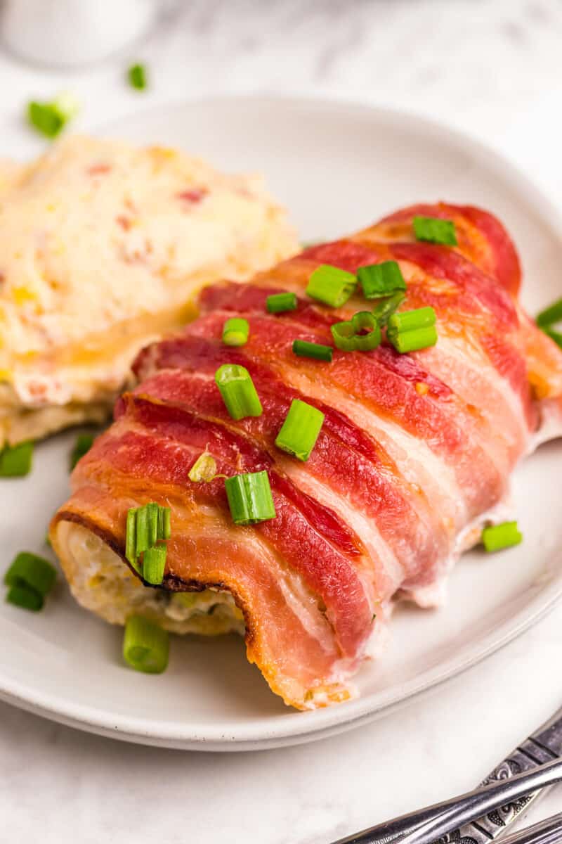 bacon wrapped stuffed chicken on white plate