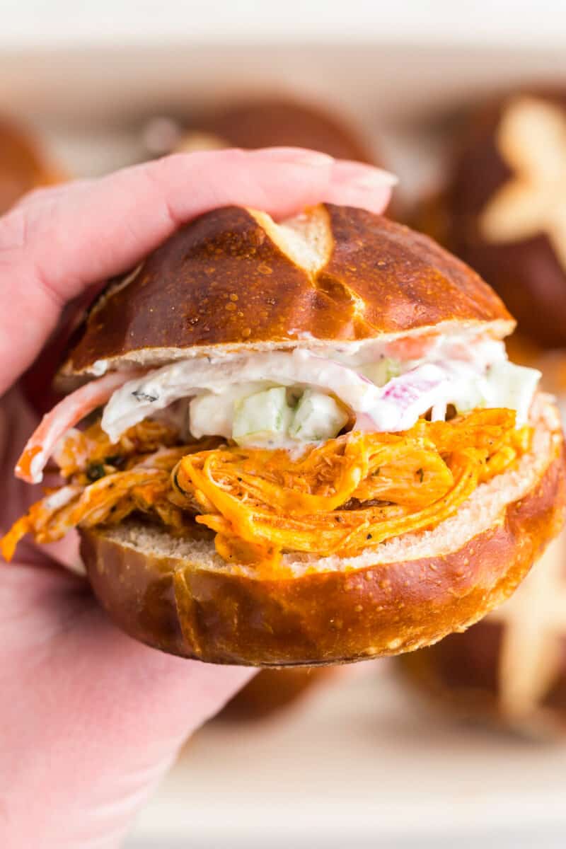 up close holding up buffalo chicken slider with bleu cheese slaw