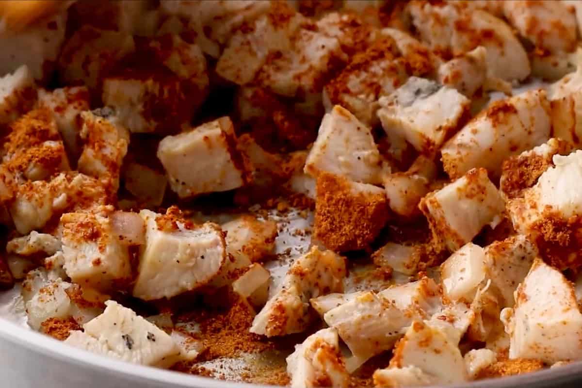 sautéed chicken and onion seasoned with taco seasoning in a pan.