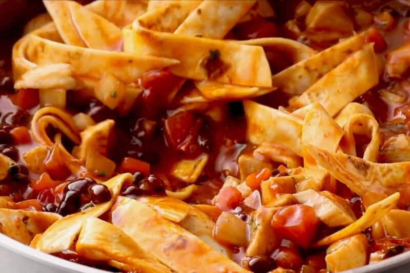 stirring tortilla strips into chicken enchilada skillet.