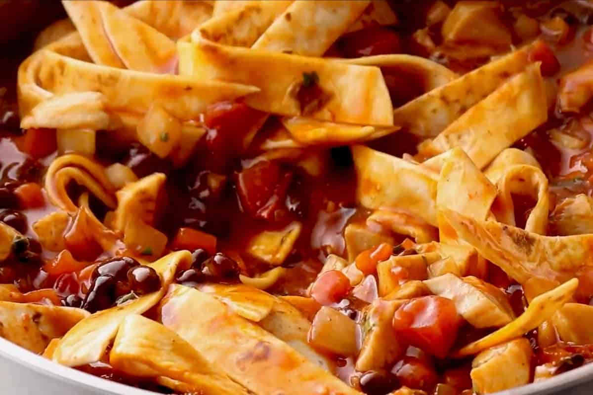 stirring tortilla strips into chicken enchilada skillet.