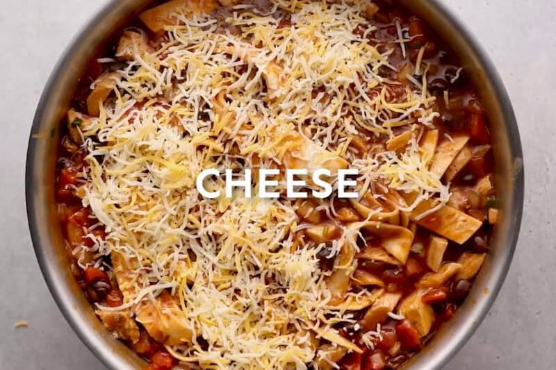 sprinkled cheese over chicken enchilada skillet with text "CHEESE" overlayed.