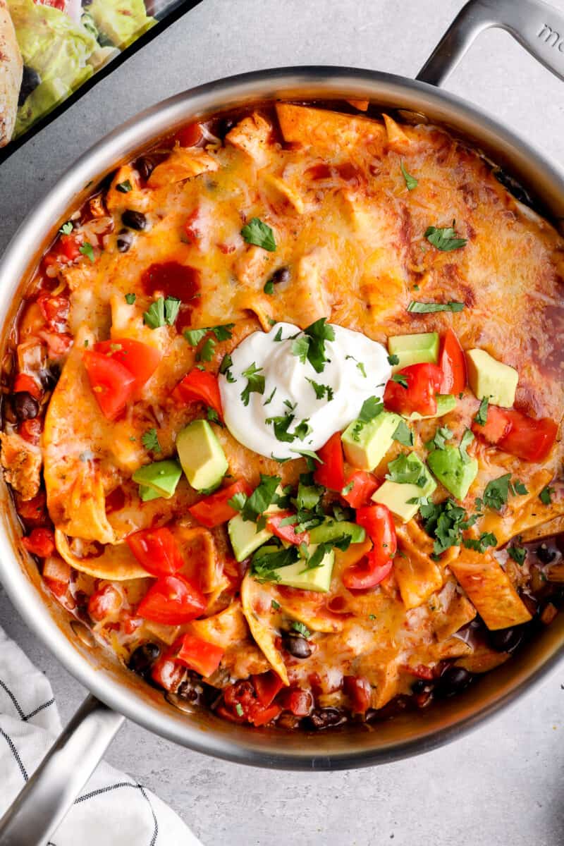chicken enchilada skillet garnished with sour cream, avocado, tomatoes, and cilantro