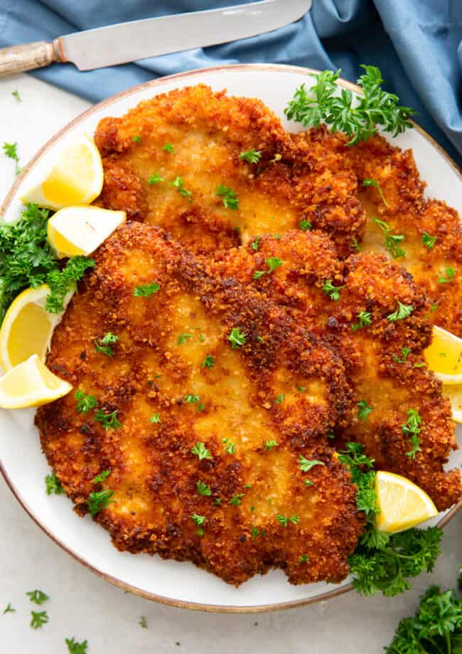 fried chicken schnitzel on plate with lemon wedges