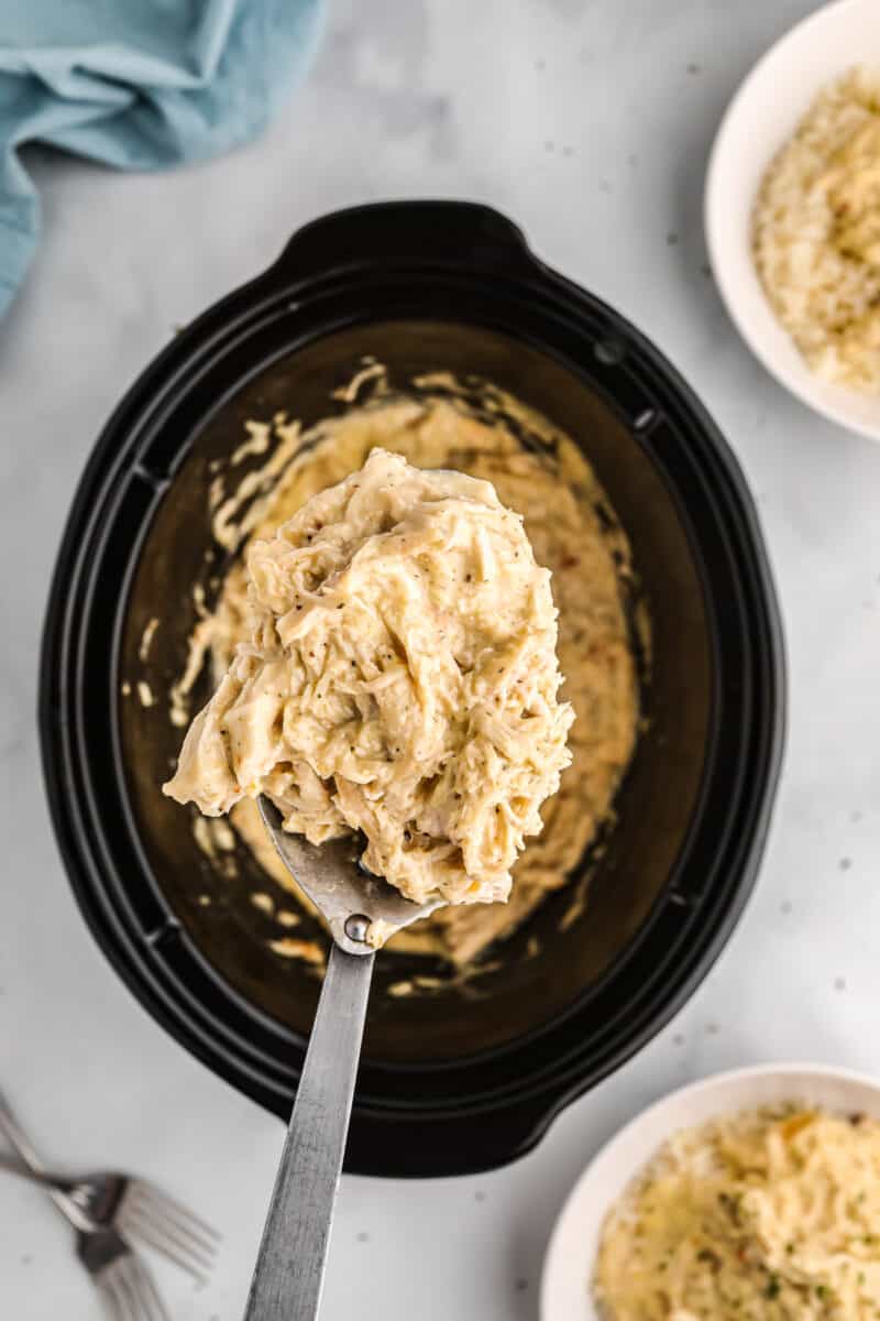 lifting up serving spoon with crockpot italian chicken