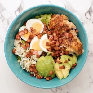 chicken cobb salad with bacon in a blue bowl.