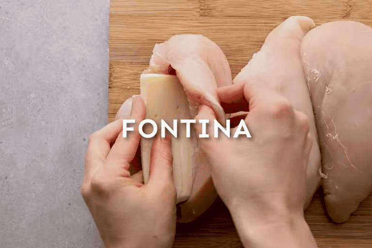 A hand stuffing fontina cheese into a raw chicken breast to make stuffed chicken marsala.
