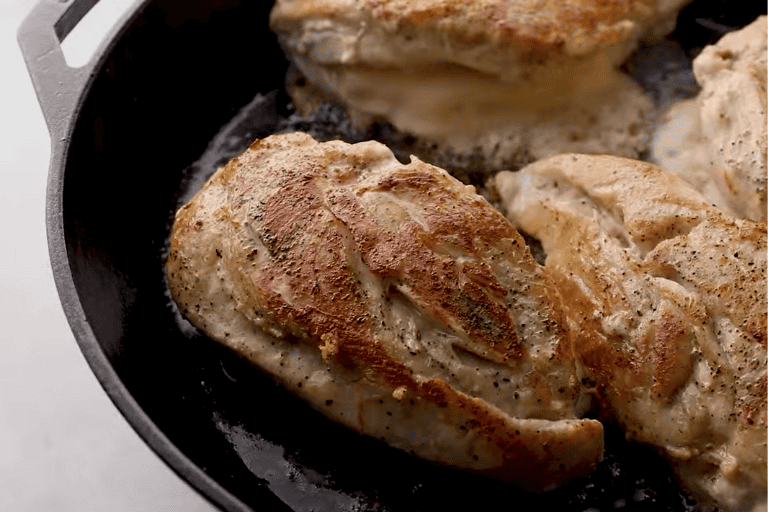 Chicken breast cooking in a hot skillet.