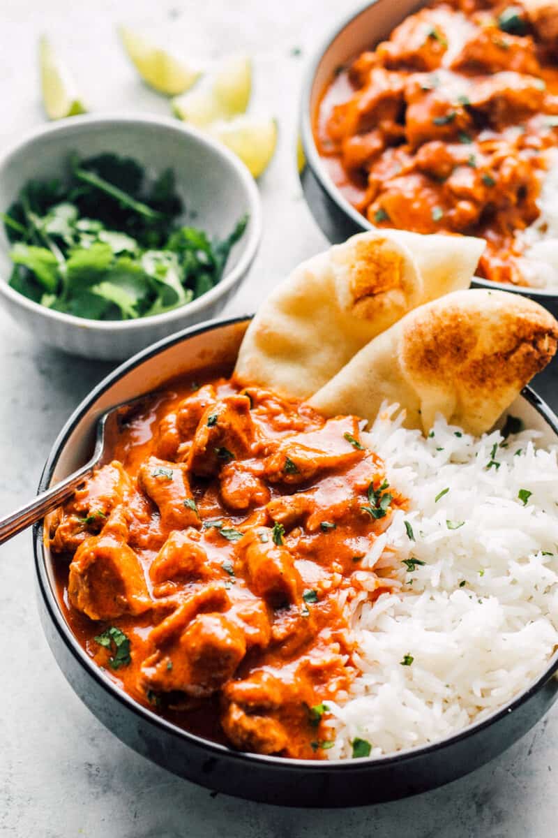 two bowls of instant pot butter chicken with rice and naan