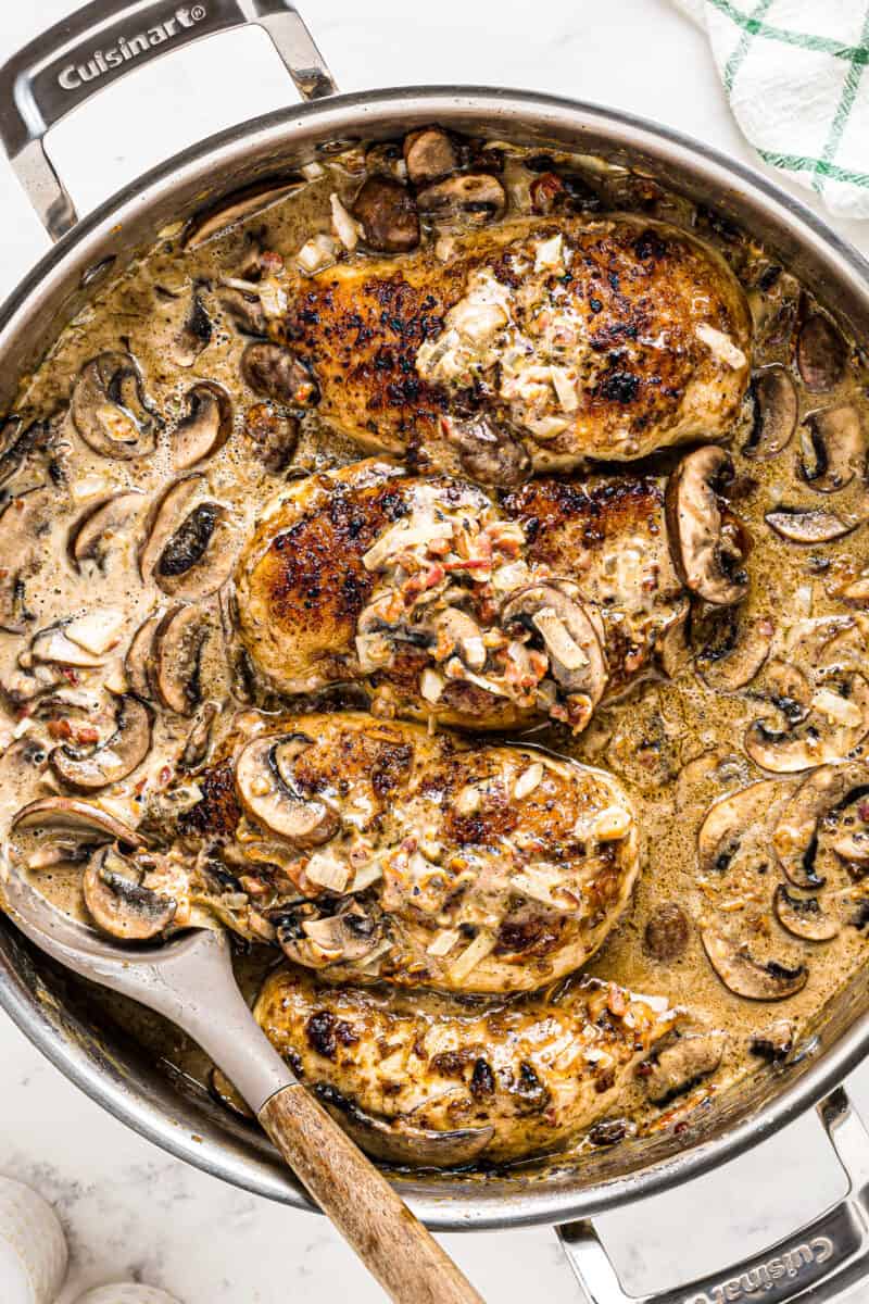 chicken breasts smothered in mushrooms, cheese, onions, and sauce in skillet