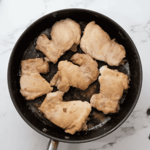 seared chicken thighs in a pan.
