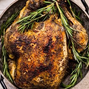 up close crockpot whole chicken in serving dish with rosemary