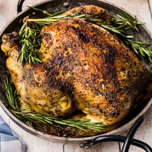 side crockpot whole chicken in serving dish with rosemary