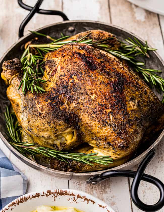 side crockpot whole chicken in serving dish with rosemary
