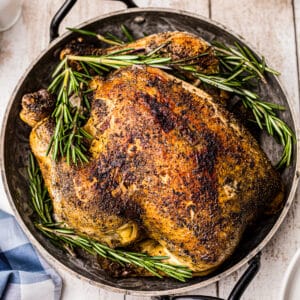 overhead crockpot whole chicken in serving dish with rosemary