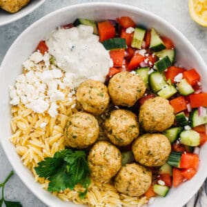 Greek chicken meatballs over veggies, rice and tzatziki sauce