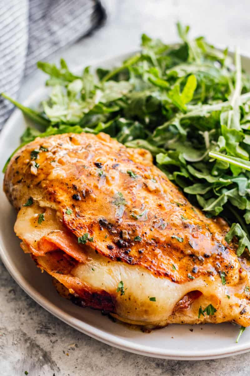 ham and cheese stuffed chicken next to a green salad