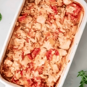 baked feta-coated chicken and tomatoes in a baking dish.