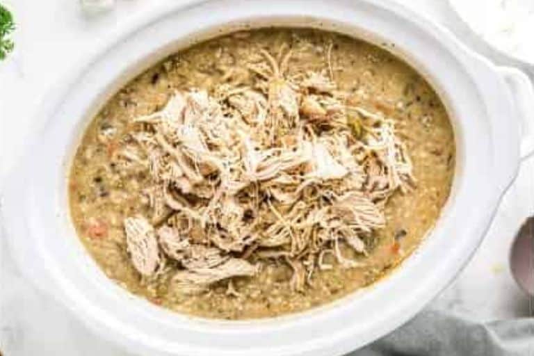 Shredded chicken in a slow cooker of wild rice soup.