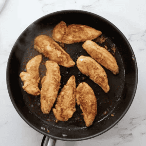 cooked seasoned chicken tenders in a pan.