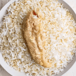 a raw, flour-and-egg-coated chicken tender in a bowl of coconut breadcrumbs.